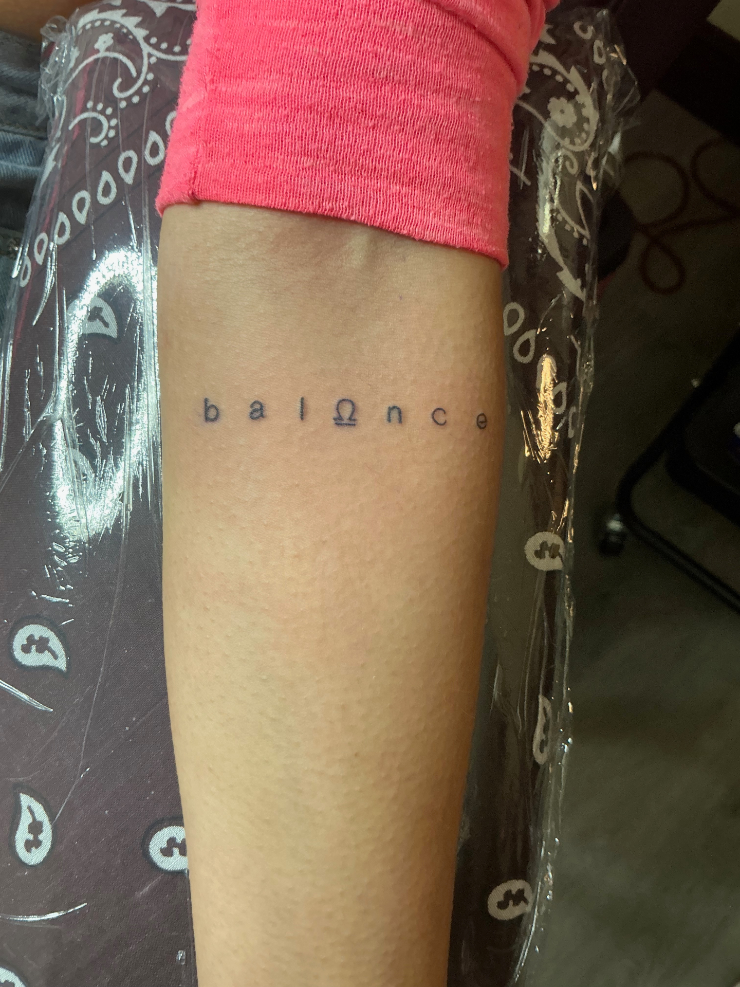 Minimal balance lettering tattoo with omega symbol