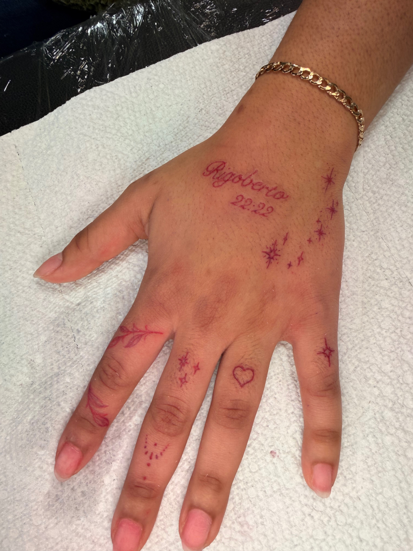 Rigoberto hand tattoo with red script, date and star accents
