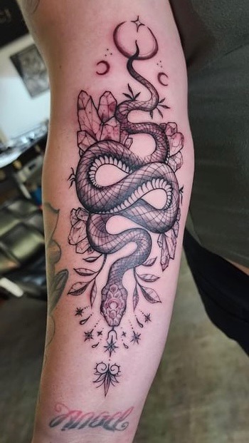 Fine line snake with crystals and botanicals forearm tattoo