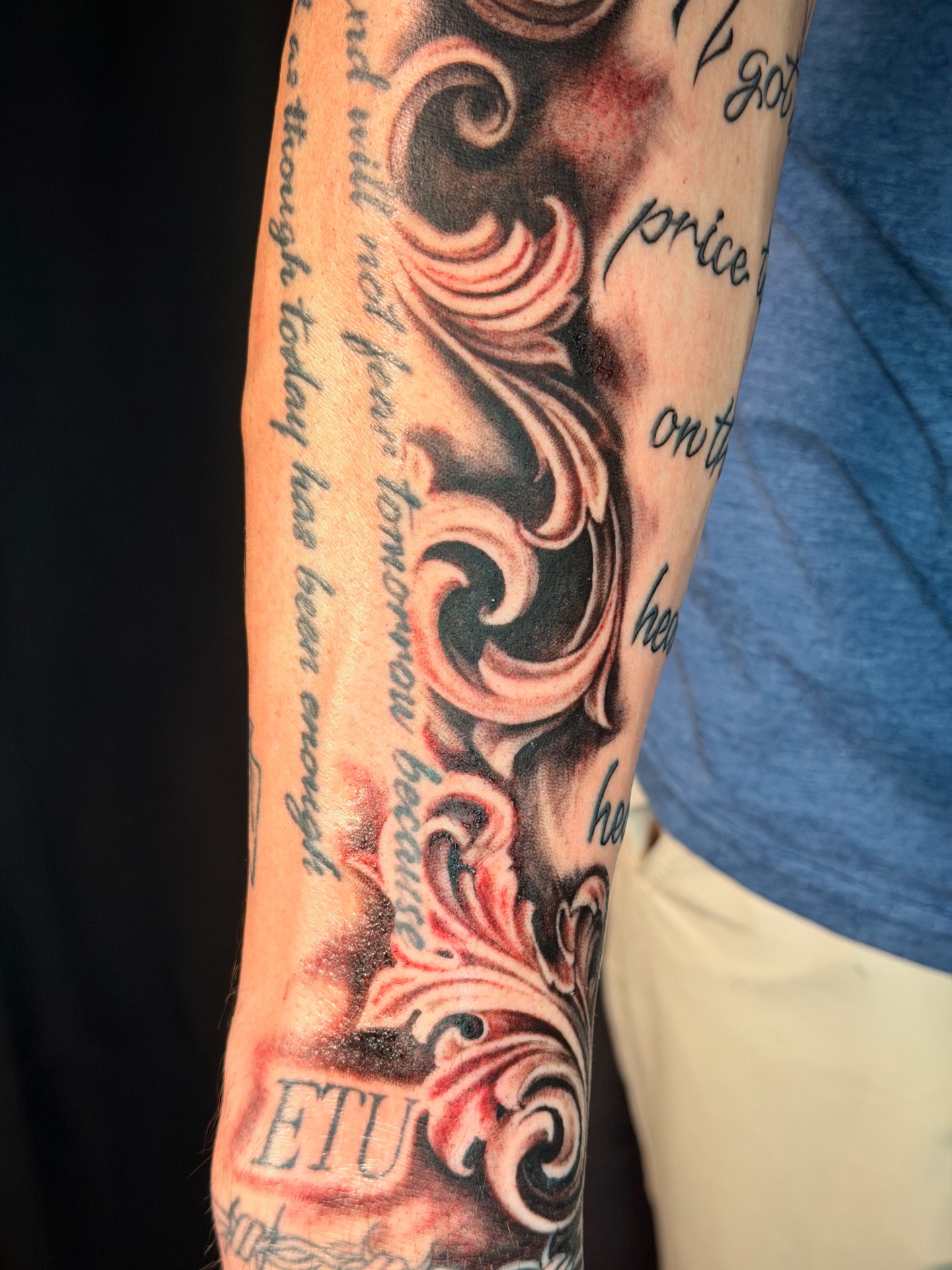 Black and grey filigree and lettering forearm sleeve tattoo