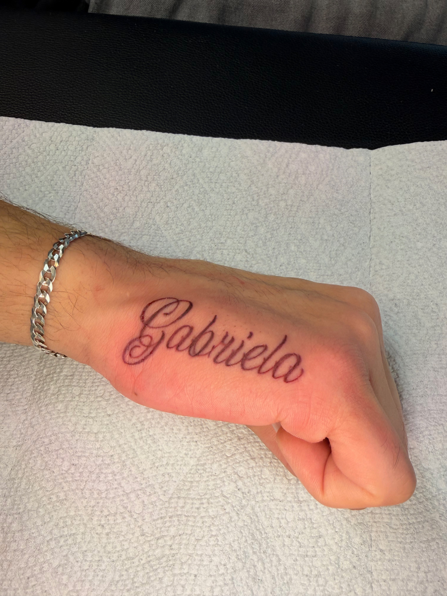 Gabriela script hand tattoo in bold cursive