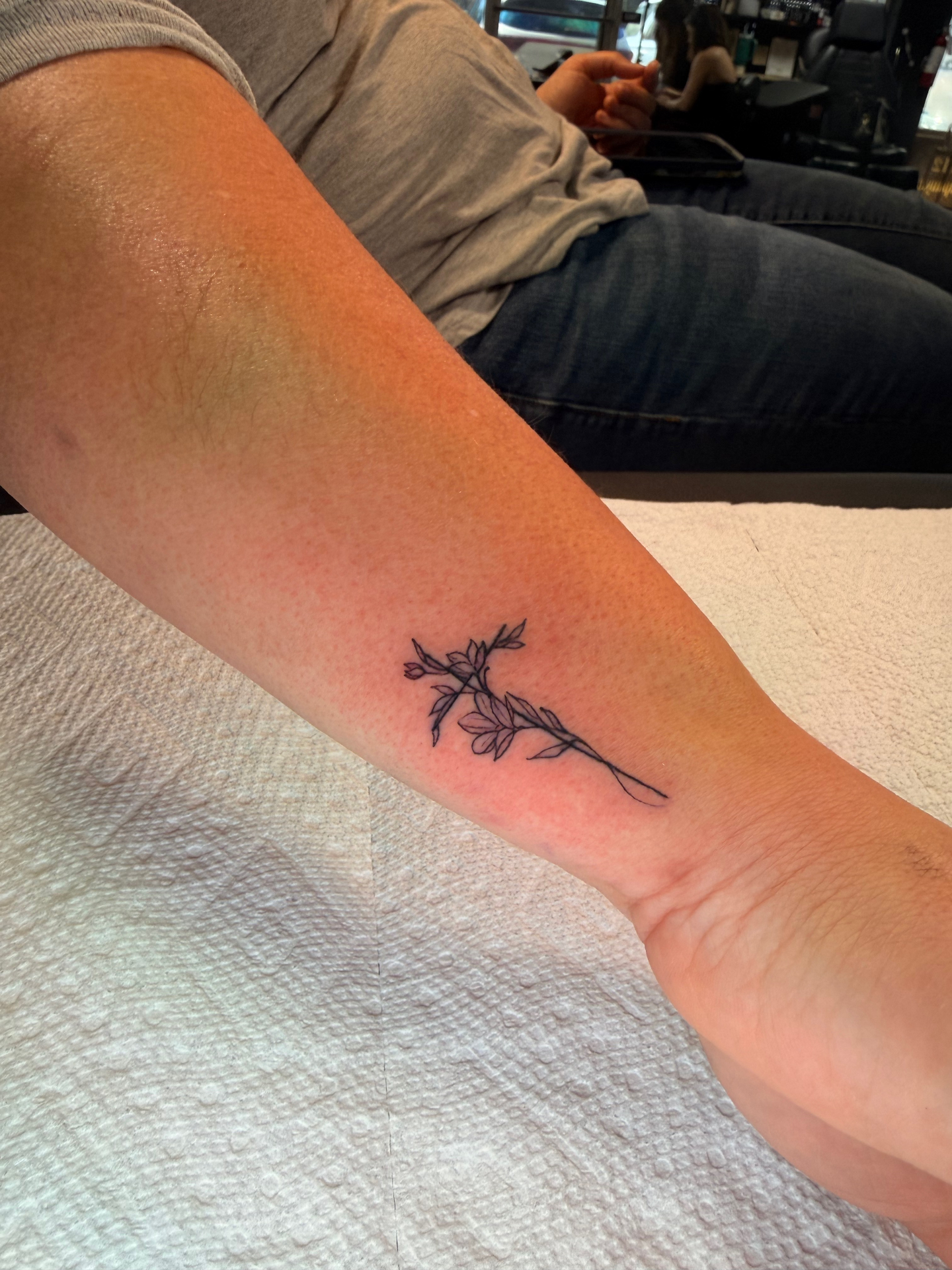 Fine line botanical sprig wrist tattoo