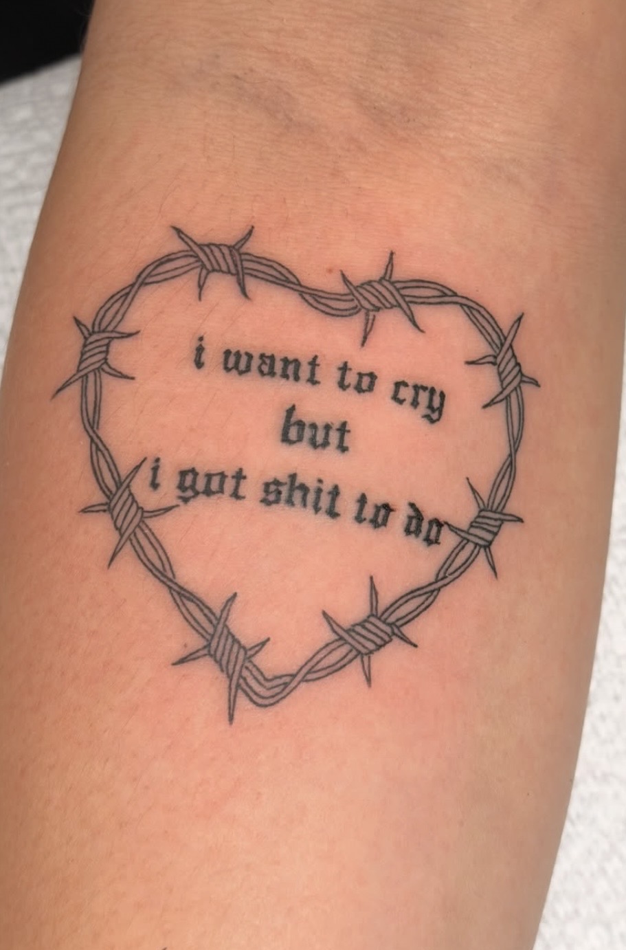 Barbed wire heart with gothic lettering tattoo