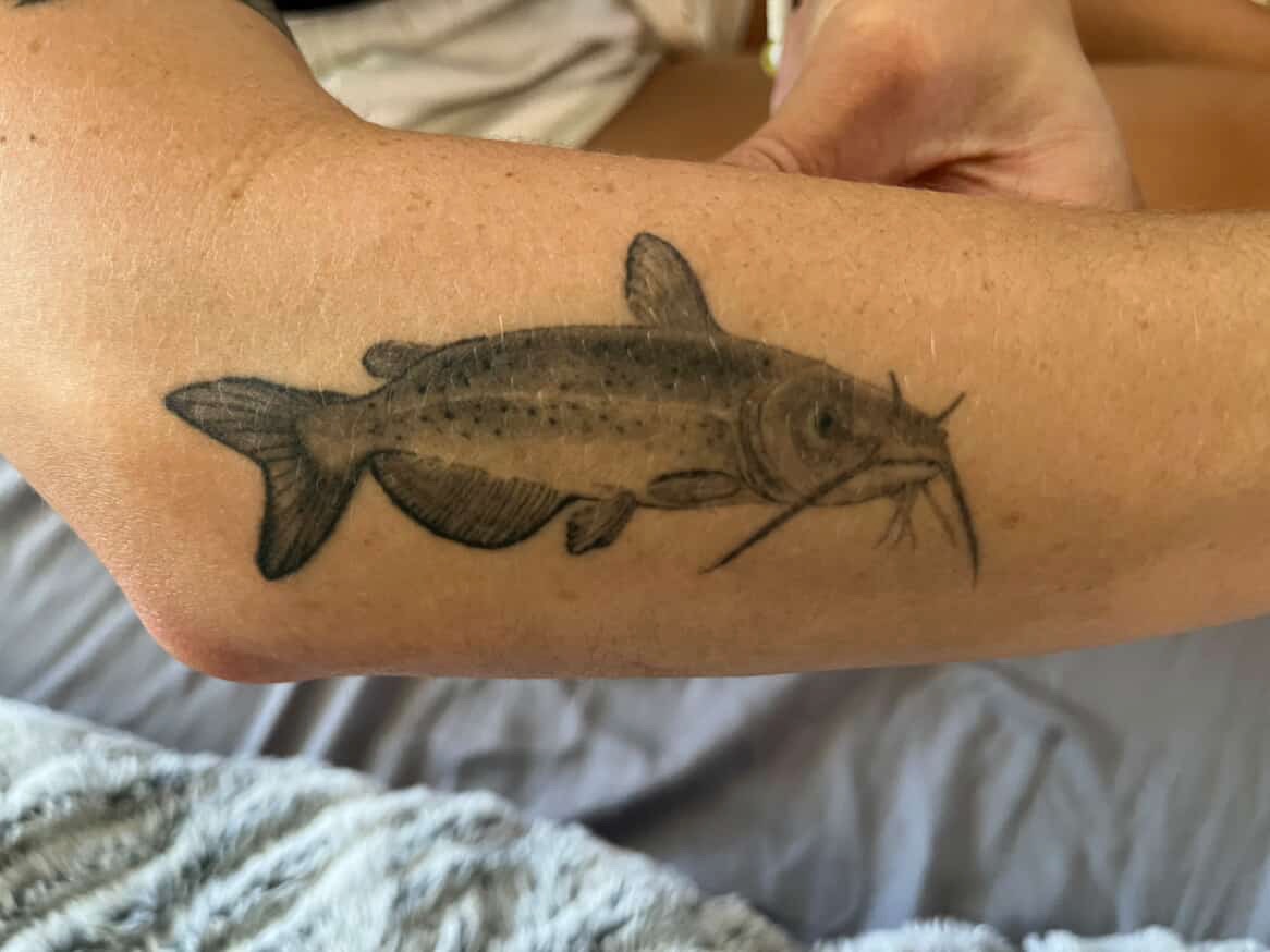 Realistic black and grey catfish forearm tattoo