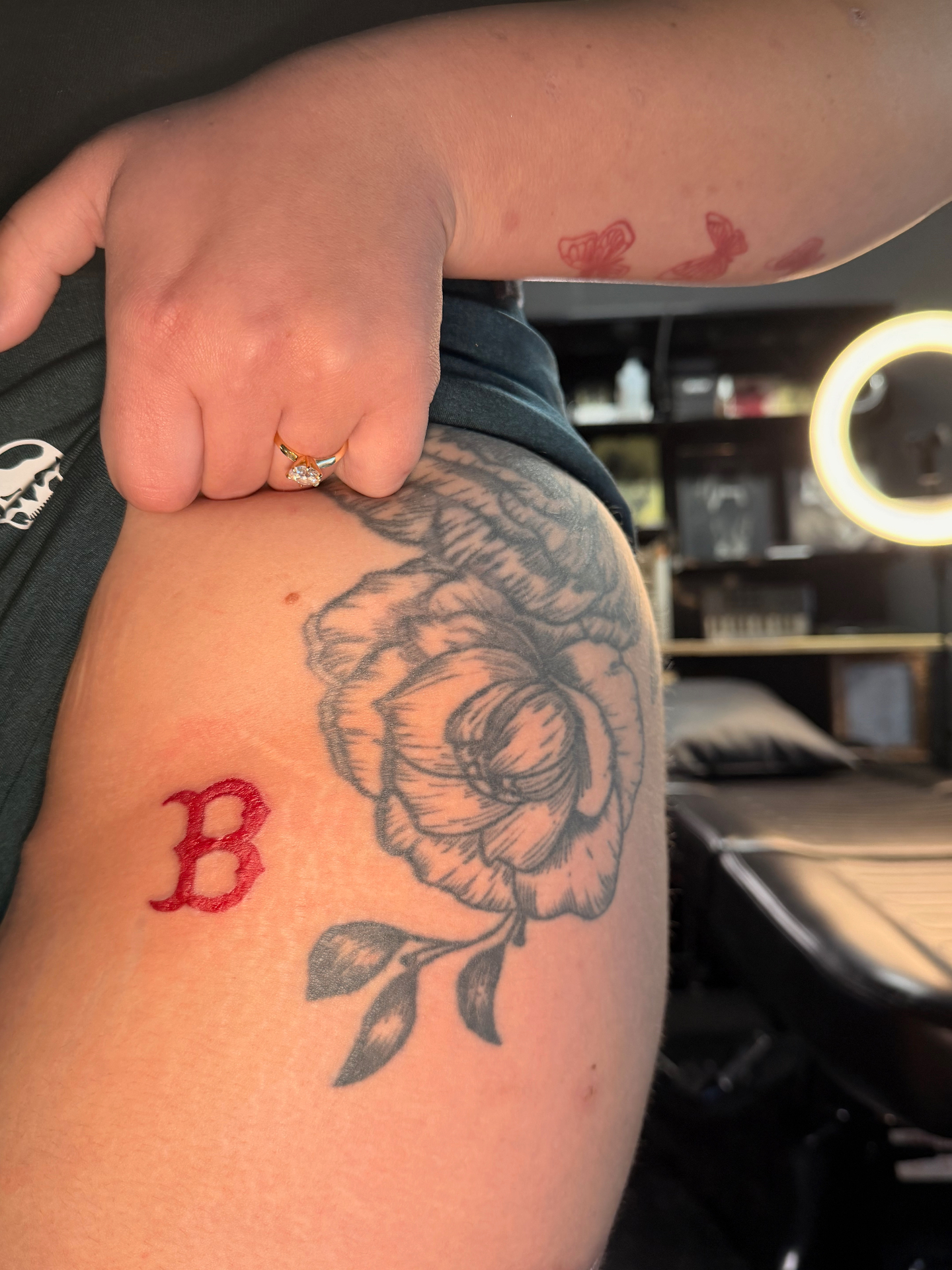 Red gothic B letter cover-up tattoo over previous ink