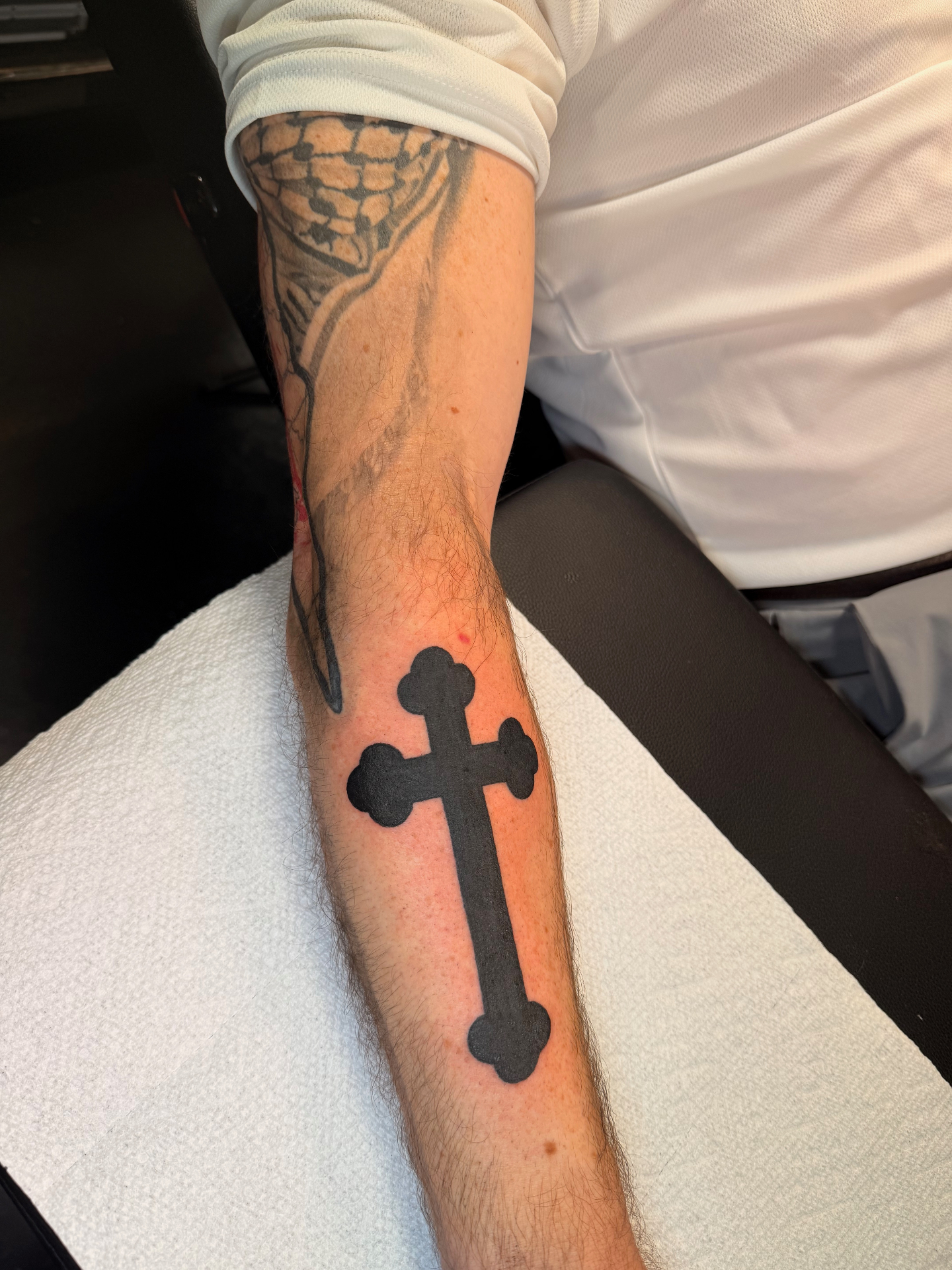 Solid black cross forearm tattoo