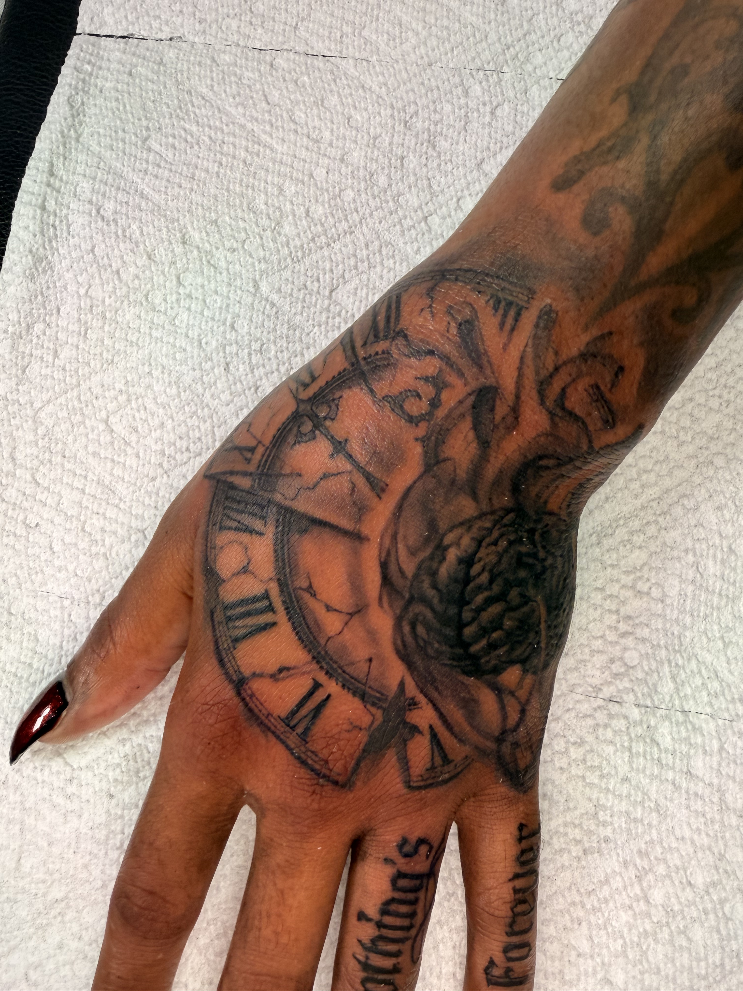 Black and grey pocket watch hand tattoo with ornamental detail