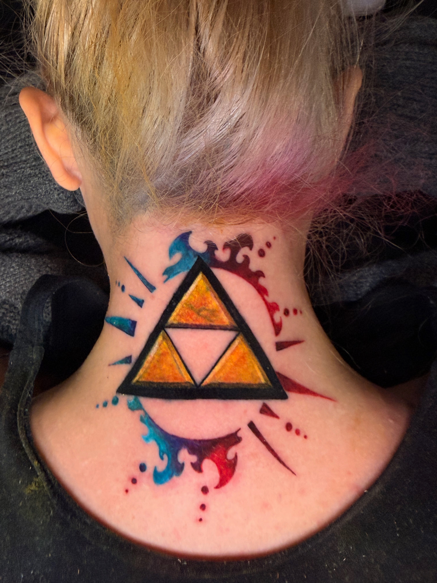 Color watercolor Zelda Triforce neck tattoo with blue and red splashes