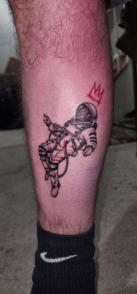 Astronaut with red crown calf tattoo