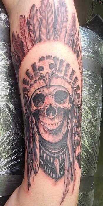 Realistic skull with feathered headdress tattoo
