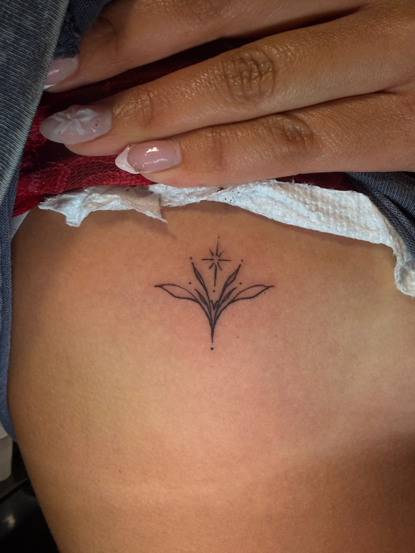Fine line ornamental starburst hip tattoo